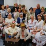 Группа людей в белорусских народных костюмах позирует в помещении Дома культуры.