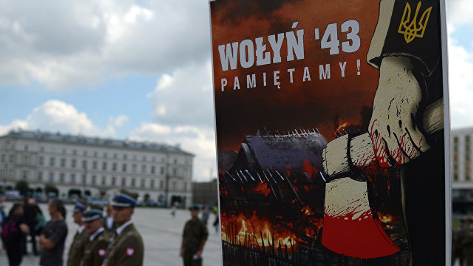 Плакат с надписью «Wołyn '43 Pamiętamy!» на фоне городской площади и людей в форме.