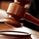 Судейский молоток над деревянной подставкой в зале суда.