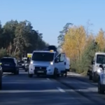 Несколько автомобилей стоят в пробке на загородной трассе среди деревьев.