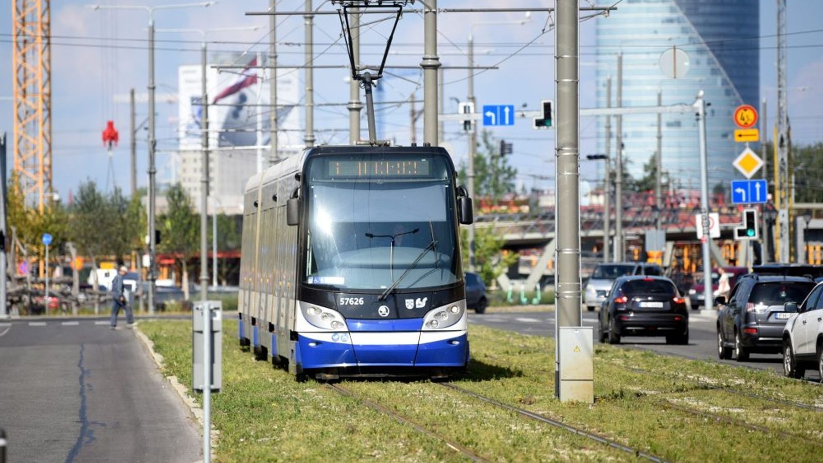 Трамвай на городских рельсах рядом с дорогой и автомобилями в Риге.