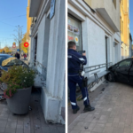 Черный автомобиль после столкновения с фасадом дома на городской улице, рядом видны полицейские и повреждения здания.