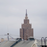 Высотное здание в городском пейзаже под пасмурным небом.