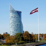 Swedbank building in Riga рядом с латвийским флагом.