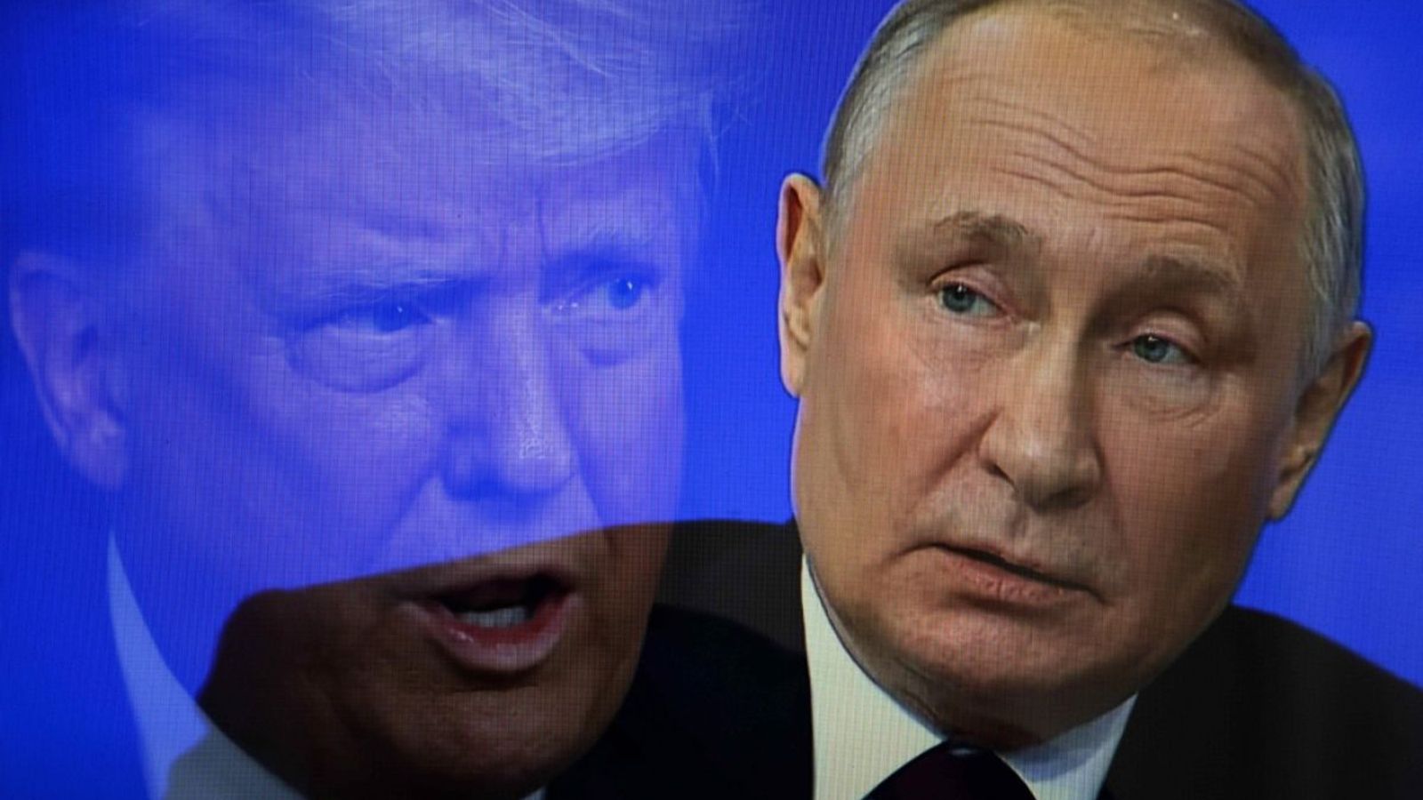 Владимир Путин на фоне синего экрана с крупным полупрозрачным изображением лица.