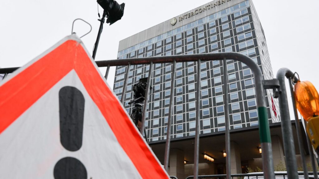 Фасад отеля InterContinental, снятый снизу за металлическими ограждениями и дорожным знаком.