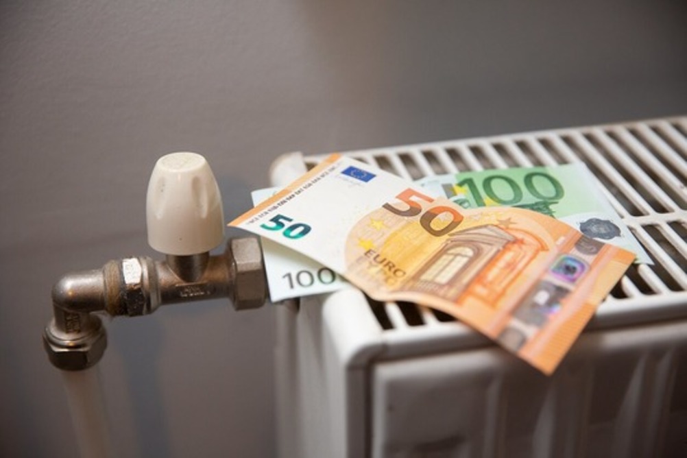 Радиатор отопления с терморегулятором и лежащими на нем евро-купюрами.