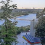 Вид на реку Днепр, пешеходный мост и городской пейзаж Киева с холма