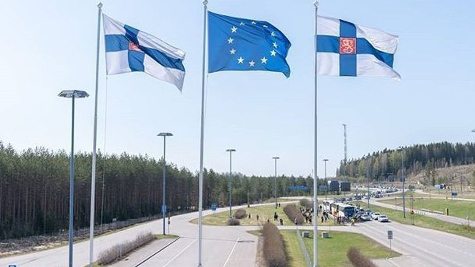 Флаги Финляндии и Европейского союза на флагштоках над дорогой.