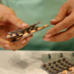 Руки медицинского работника держат блистеры с таблетками.