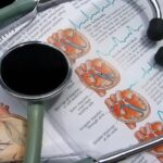 Стетоскоп лежит на странице с медицинской схемой сердца и кардиограммами.