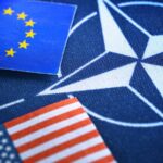 Значок НАТО на фоне флагов ЕС и США.