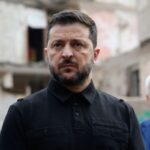 Володимир Зеленський на фоне разрушенного здания во время визита.