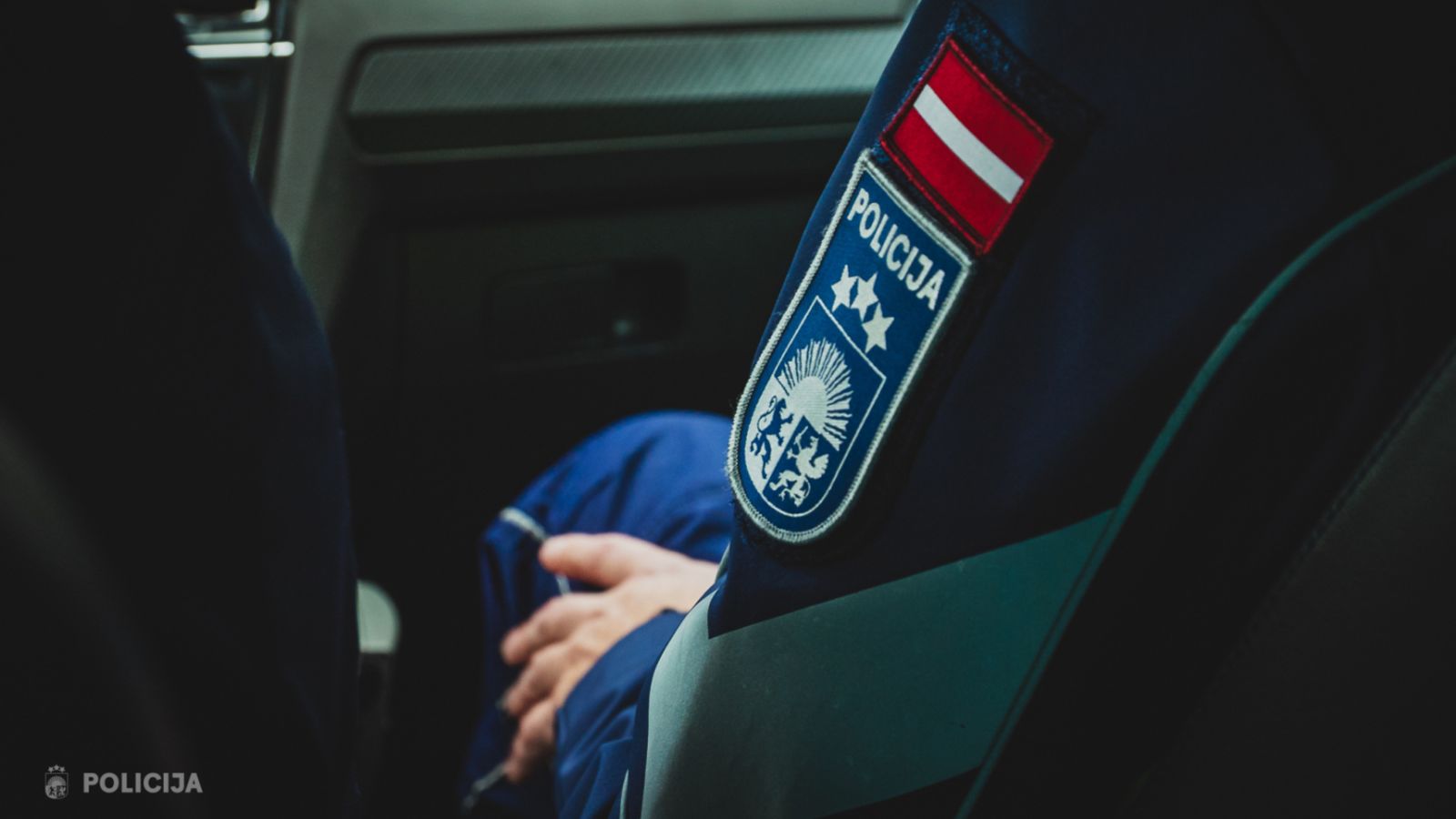 Патч полиции Латвии на форме сотрудника в салоне автомобиля.