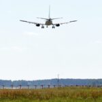 Самолет на заходе на посадку над взлетно-посадочной полосой аэропорта.