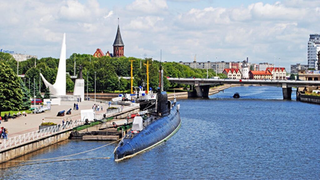 Подводная лодка у набережной на фоне центра Калининграда и моста через реку.