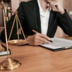 Юрист за столом с документами и символом правосудия — весами.