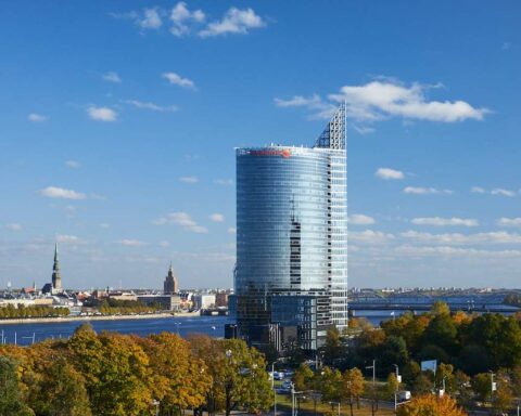 Skyscraper Swedbank в городском пейзаже на фоне реки и неба.