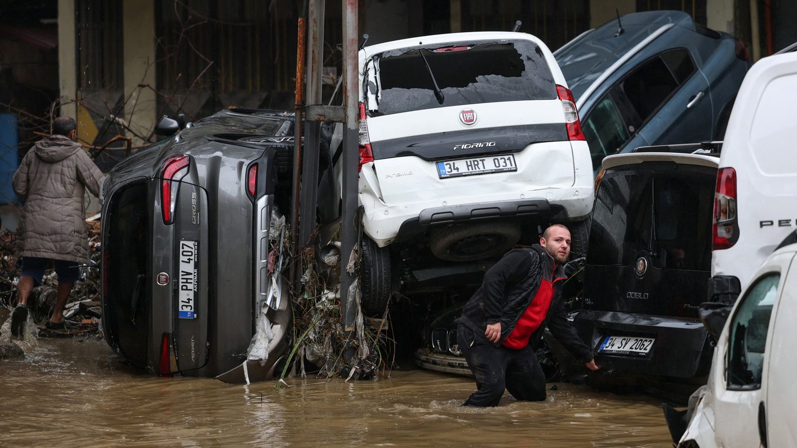 Затопленная улица в Стамбуле с перевернутыми автомобилями и людьми в воде.
