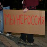 Участники протеста держат картонные плакаты с надписью «Мы не Россия».