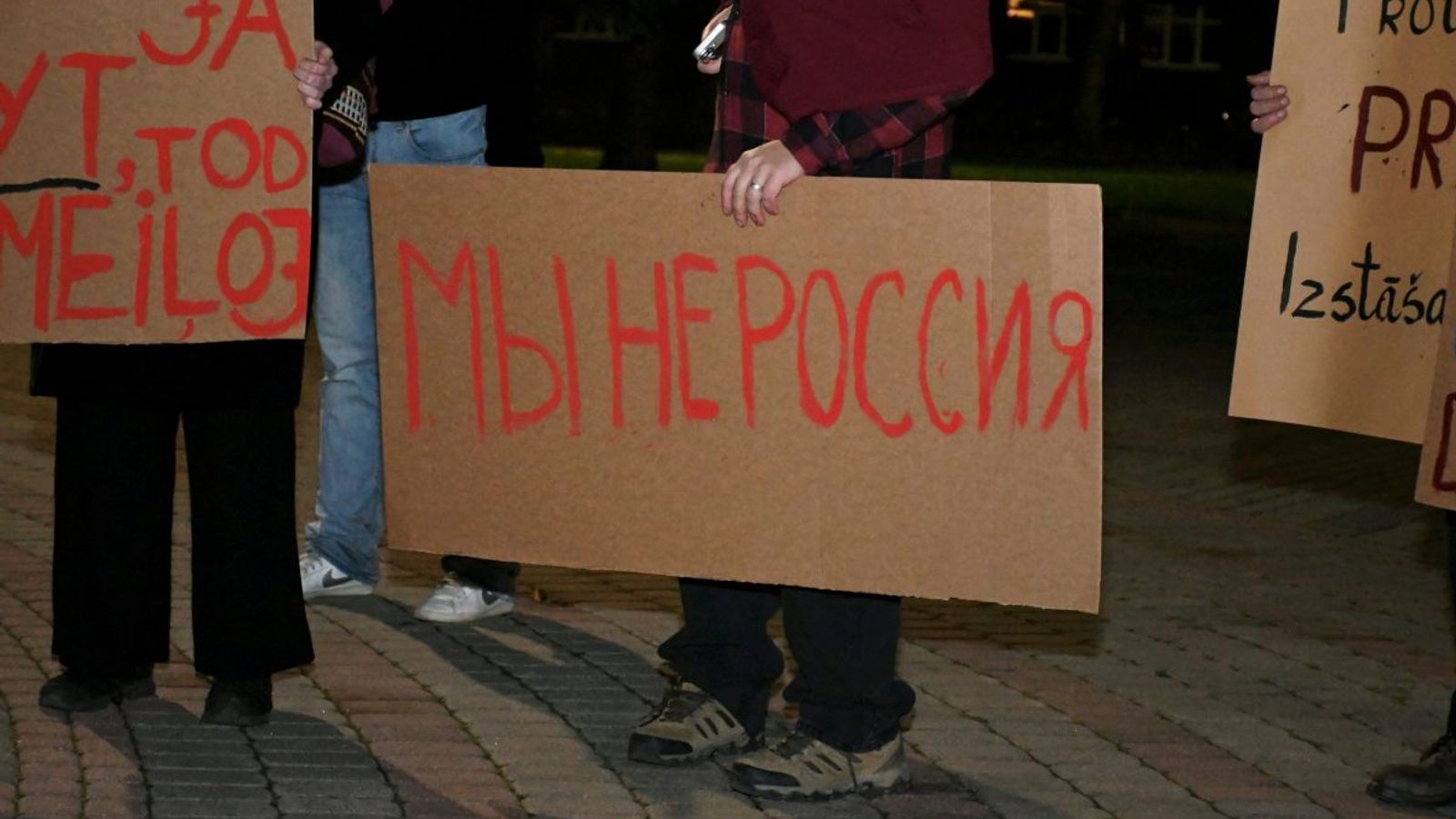 Участники протеста держат картонные плакаты с надписью «Мы не Россия».